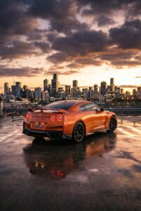 Rear view of a luxury orange sports car parked during a golden hour sunset.