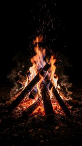 Vertical ultra-realistic digital art of a cozy campfire burning in the dark wilderness, showing glowing orange embers, flying sparks, and realistic smoke against a true pitch-black background, 4K AMOLED dark aesthetic wallpaper.