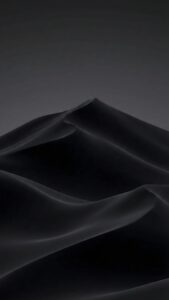 Vertical abstract dark wallpaper featuring smooth black waves resembling silk fabric or sand dunes at night, minimalist monochrome texture, soft lighting, 4K AMOLED background