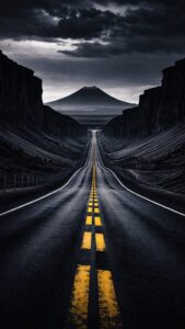 Vertical cinematic photography of an endless empty dark asphalt road with bright double yellow lines leading towards a distant solitary mountain peak, flanked by steep dark canyon walls under a moody overcast sky, 4K AMOLED wallpaper
