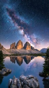 Highly detailed digital landscape photography of majestic rocky mountain peaks reflecting in a calm serene lake under a breathtaking starry night sky with the milky way galaxy and shooting stars aesthetic 4K ultra HD mobile wallpaper