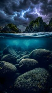 Highly detailed 4K split-level photography showing moody stormy clouds and mossy rocks above water, and clear turquoise water with smooth textured rocks below, optimized for iPhone depth effect wallpaper.