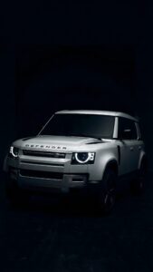 Highly detailed digital render of a pristine white Land Rover Defender luxury SUV with glowing circular LED headlights parked in a pitch black dark studio setting premium automotive aesthetic 4K ultra HD mobile wallpaper