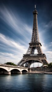 A high-resolution 4K mobile wallpaper of the Eiffel Tower in Paris standing tall behind a stone bridge over the Seine River with a cinematic blue sky.