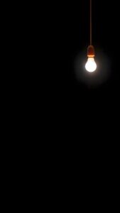 True AMOLED 4K mobile wallpaper featuring a minimalist glowing light bulb hanging against a pitch-black dark background.