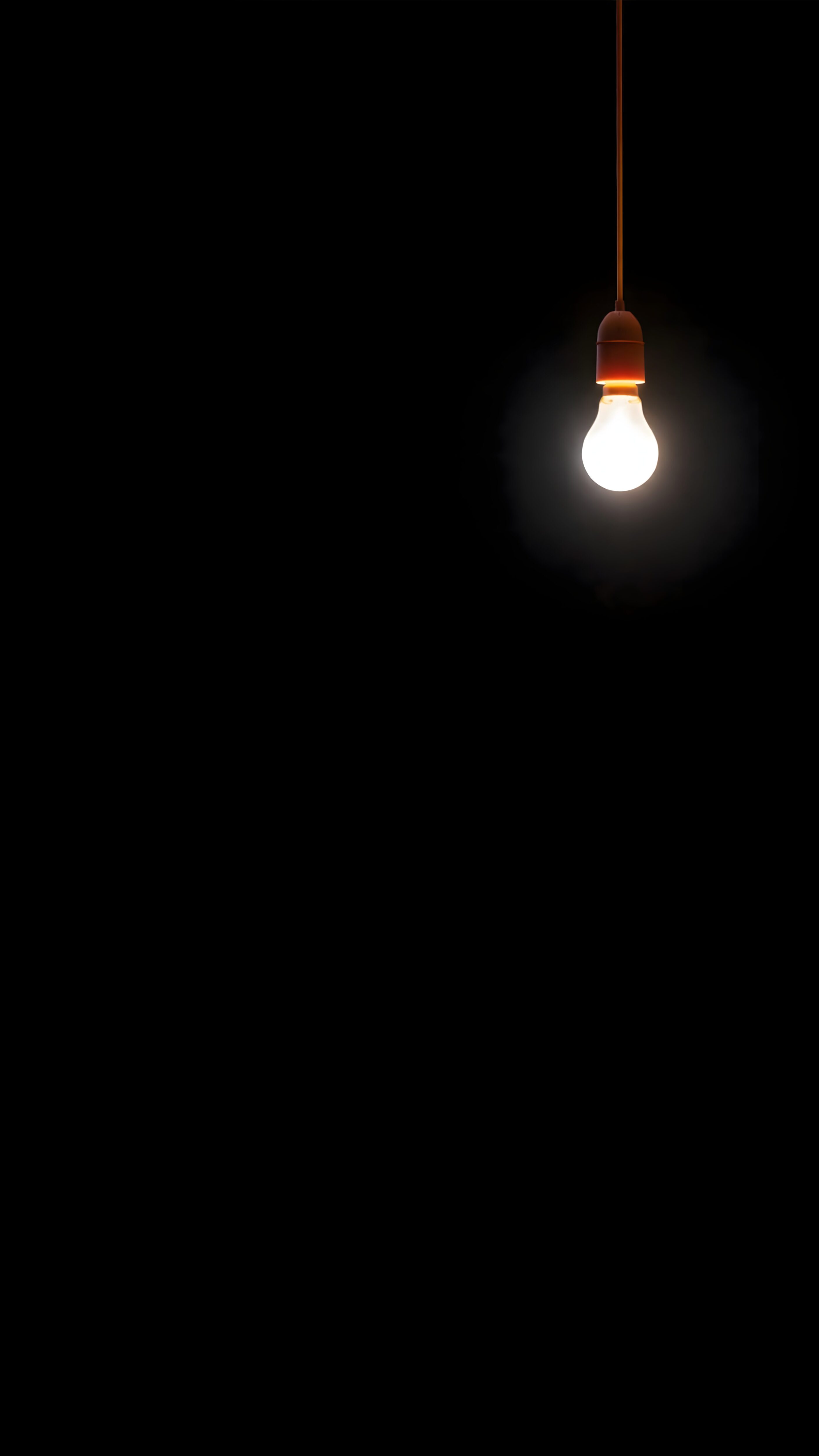 True AMOLED 4K mobile wallpaper featuring a minimalist glowing light bulb hanging against a pitch-black dark background.