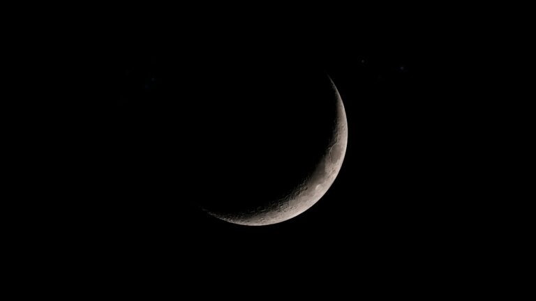 Detailed crescent moon glowing against a pitch-black starry night sky space background.