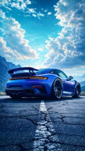 Rear view of a sleek, electric blue sports car parked on cracked asphalt under a bright, cloudy sky with mountains in the background.