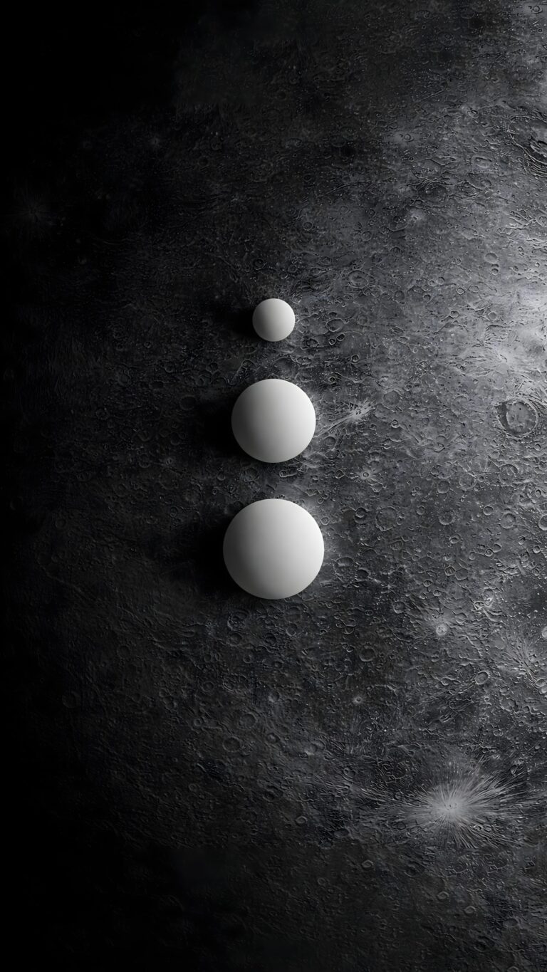 Three smooth white spheres stacked vertically by size on a dark, textured cratered lunar surface.