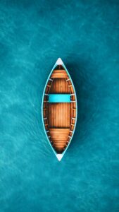 A high-angle, top-down view of an empty wooden boat floating peacefully on bright turquoise ocean water.