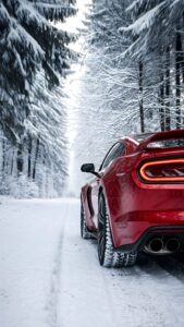 Red muscle car parked on a snow-covered dirt road surrounded by frosty pine trees in a dense winter forest.