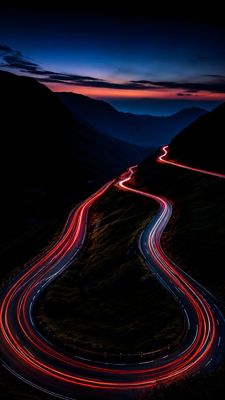 A dark mountain valley at twilight featuring a winding path of bright red glowing light trails under a deep blue night sky.