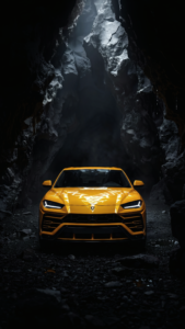 Bright yellow Lamborghini Urus parked inside a dark, rocky cave with dramatic overhead lighting.