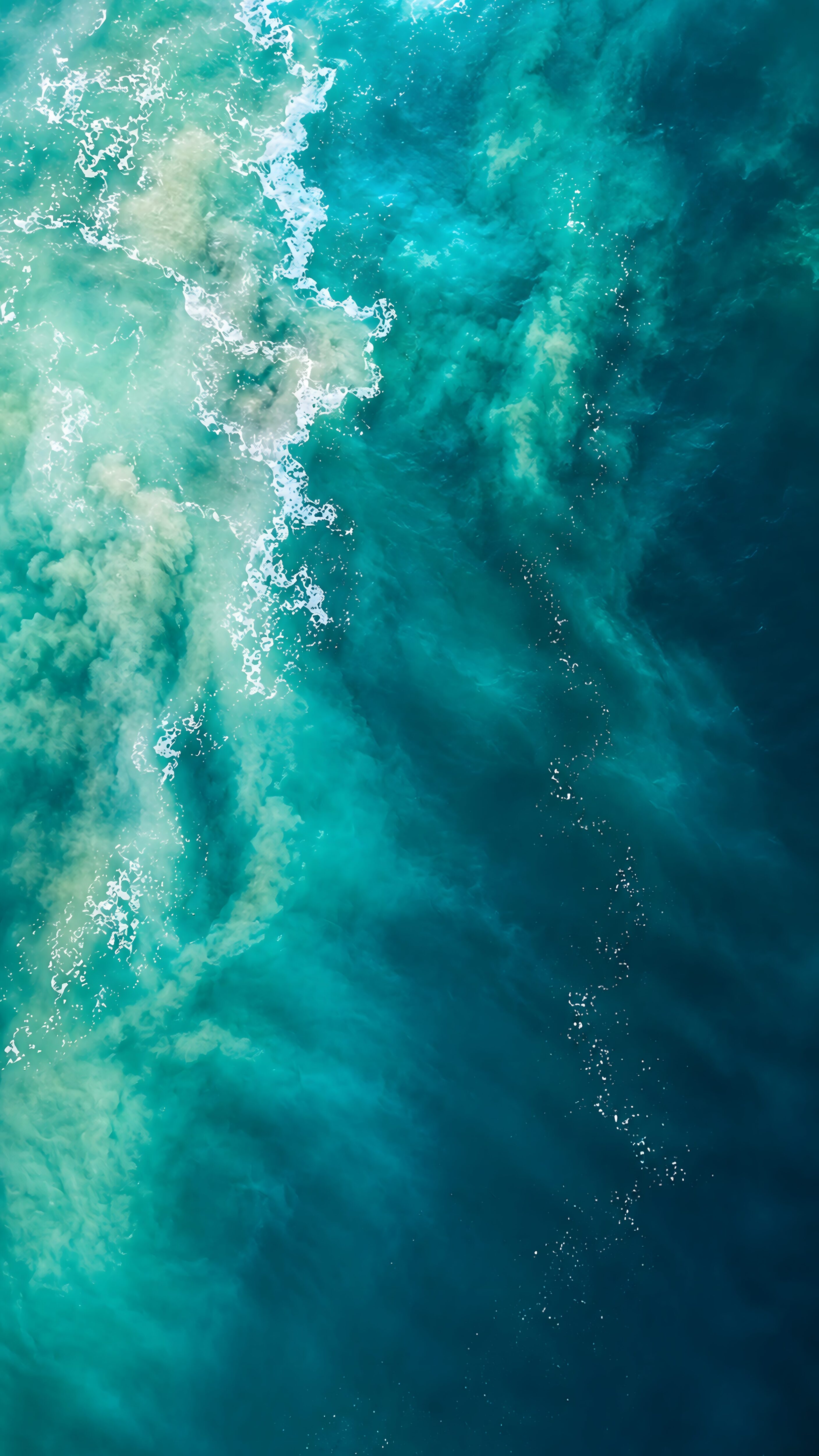 Aerial view of swirling turquoise ocean water and deep blue sea currents.