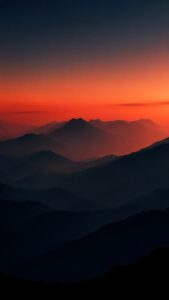 A vertical wallpaper showing silhouettes of layered mountain ranges under a vibrant deep orange and red sunset sky.