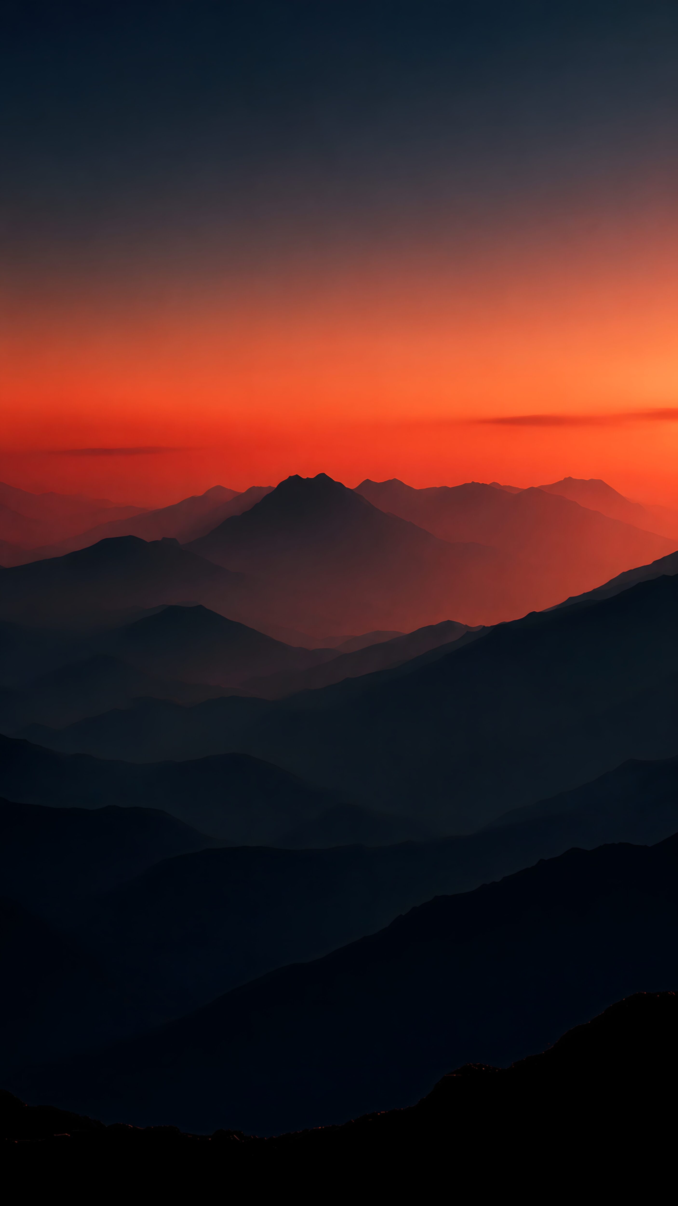 A vertical wallpaper showing silhouettes of layered mountain ranges under a vibrant deep orange and red sunset sky.