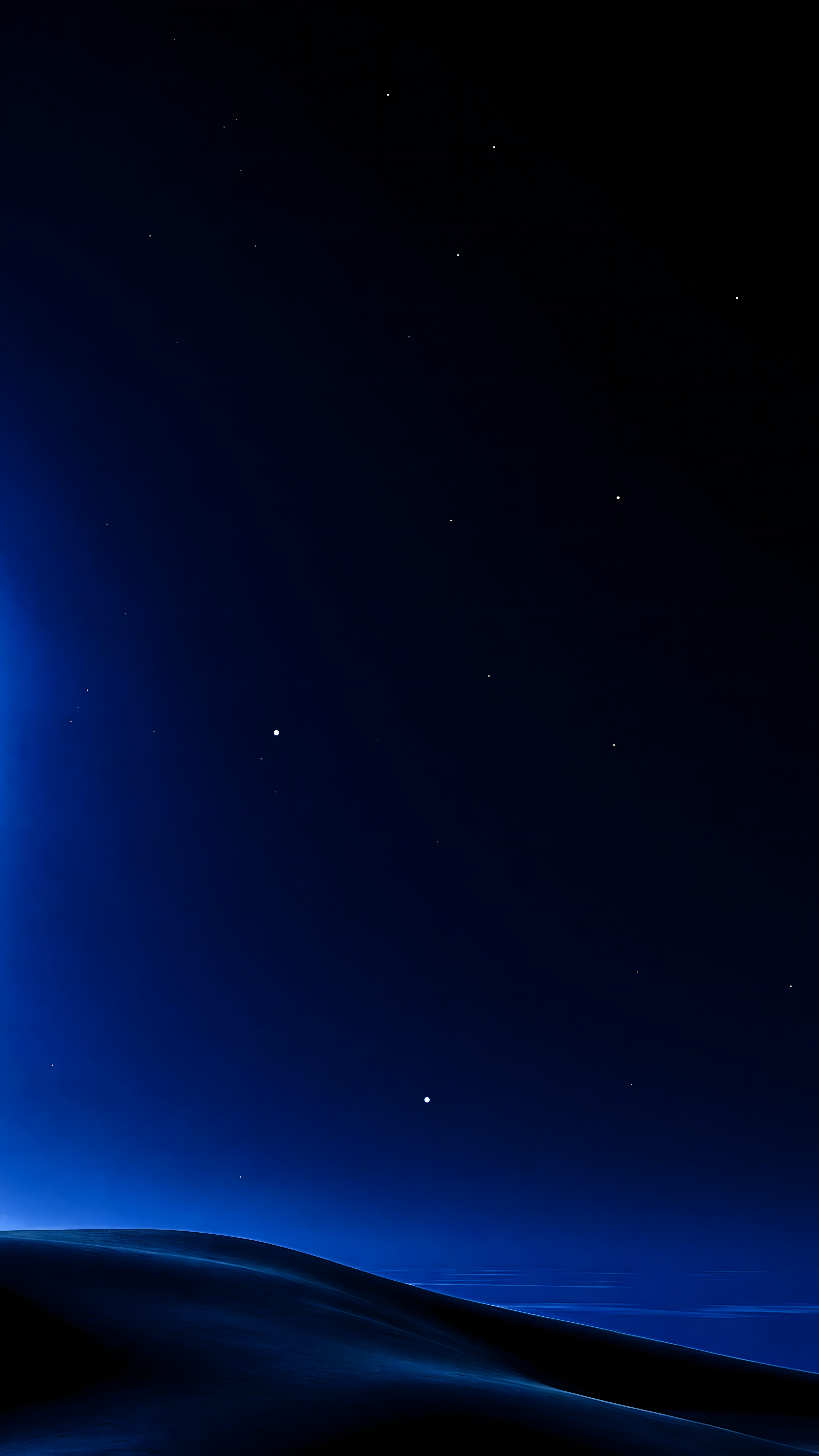 A dark blue night sky featuring scattered bright stars over a smooth, shadowy horizon line.